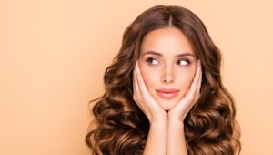 Young Female Model with Brown Wavy Hair Framing Head with Hands