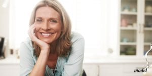 Happy Middle Aged Woman Leaning Over Counter Resting her Chin in her Hand | Westfield Plastic Surgery Center Happy Middle Aged Woman Leaning Over Counter Resting her Chin in her Hand